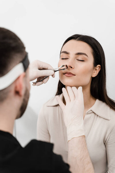 Rhinoscopy of woman nose. Consultation with ENT doctor. Otolaryngologist examines girl nose before procedure of endoscopy of nose