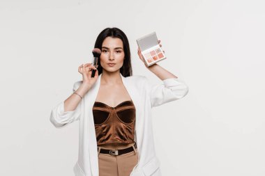 Yüzüne yakın fırça ve palet ile makyaj sanatçısı. Profesyonel kozmetik göz farı, allık ve bronzlaştırıcı mükemmel cilt için makyaj sanatçısı.