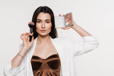 Yüzüne yakın fırça ve palet ile makyaj sanatçısı. Profesyonel kozmetik göz farı, allık ve bronzlaştırıcı mükemmel cilt için makyaj sanatçısı.