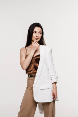 Çekici model dudaklarına mat pastel ruj sürmüş. Makyöz kız dudaklarını beyaz arka planda rujla boyuyor.