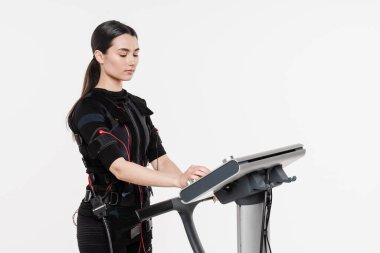Beyaz arka planda EMS kıyafetli kız. Elektrik kas stimülasyonu giysisinde spor eğitimi
