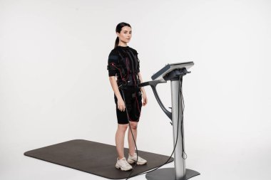 Beyaz arka planda EMS kıyafetli kız. Elektrik kas stimülasyonu giysisinde spor eğitimi