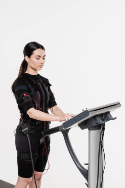 Beyaz arka planda EMS kıyafetli kız. Elektrik kas stimülasyonu giysisinde spor eğitimi