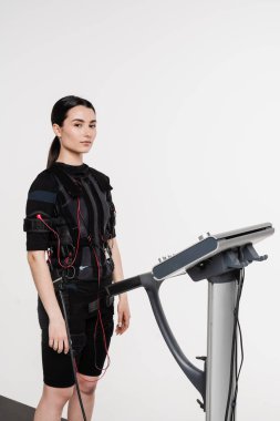 Beyaz arka planda EMS kıyafetli kız. Elektrik kas stimülasyonu giysisinde spor eğitimi