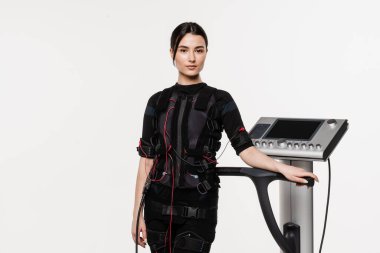 Beyaz arka planda EMS kıyafetli kız. Sağlık görevlisi kız antrenörü, acil servis giysisiyle antrenmandan önce. Elektrik kas stimülasyonu giysisinde spor eğitimi