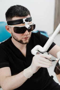 Koruyucu gözlüklü KBB doktoru elinde cerrahi lazerle burun astarında lazer tedavisi, burun akıntısı, hapşırma belirtileri gösteriyor. Lazerle kronik rhinitis tedavisi