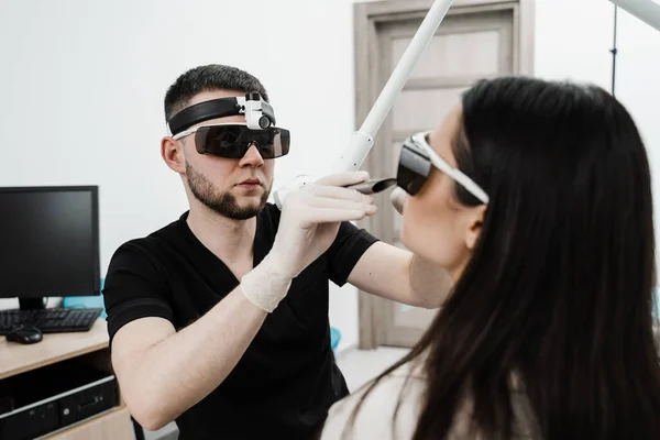 stock image ENT doctor in protective glasses holding surgical laser and doing laser treatment inflammation of the nasal lining, runny nose, sneezing symptoms. Chronic rhinitis treatment with laser