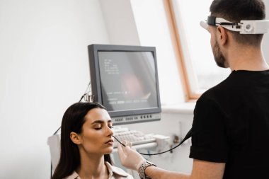 KBB doktoru burnu incelemek ve tedavi etmek için fibrolaryngoskop kullanıyor. ENT uzmanları gırtlak ve gırtlak, gırtlak düğümleri, ses teli nodülleri, tümörler, enfeksiyonlar ve iltihaplanma gibi hastalıkları teşhis eder ve tedavi eder.