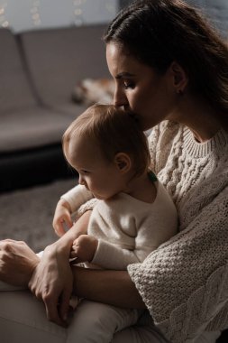 Anne mutfakta küçük kızına sarılıyor ve onu öpüyor. Doğumhane. Mon ve oğlu evde birlikte vakit geçiriyorlar.