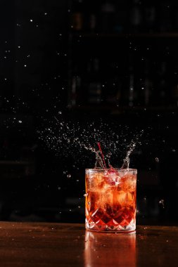 Kiraz düşmesi ve Negroni 'nin alkollü kokteyline sıçraması. Barmen barda Negroni kokteyli hazırlıyor.