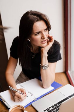 Dizüstü bilgisayarı olan üzgün bir kızın ağrısı yüzünden migreni tuttu. Güçlü baş ağrısı olan bir kadın yönetici tavan arası kafede bilgisayarla çalışıyor.