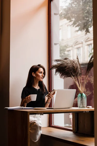 Confident business woman is chatting using laptop with colleagues via video connection and discussing new ideas. Happy girl with laptop is chatting with her friends and family in cafe