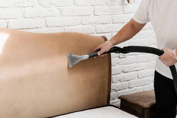 Dry wash cleaner is removing dirt and dust from bed headboard using dry cleaning extraction machine. Process of extraction dirt from headboard of bed using extractor cleaning machine