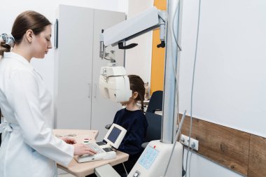 Kırılma hatasını ölçmek ve gözlük reçetesi için bilgi belirlemek için phoropter. Çocuk, pediatrik göz doktorunun göz muayenesi sırasında phoropter 'e bakar.