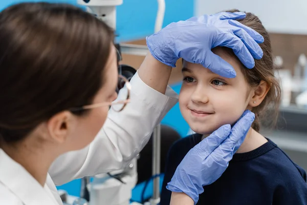 Pediatric ophthalmologist examines eyes and pupil of child. Consultation for children at ophthalmological clinic for treatment of eye inflammation and vision correction