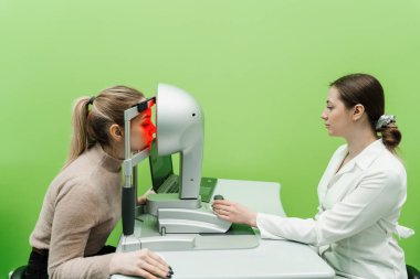 Korneanın şekli ve gücünün görsel tanımı için kornea topografisi göz görme testi. Optometrist göz hekimliği kliniğindeki kerato topografını kullanarak hastaların gözlerini tarıyor.