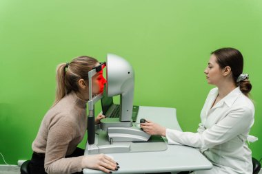 Korneanın şekli ve gücünün görsel tanımı için kornea topografisi göz görme testi. Kornea topografının kırmızı ışığı topoğrafya sınavında kadının üzerine parlıyor