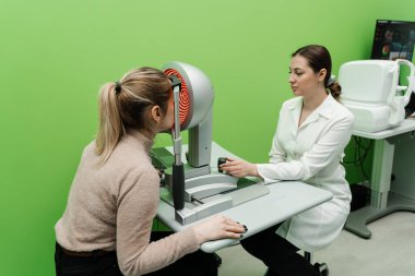 Korneanın şekli ve gücünün görsel tanımı için kornea topografisi göz görme testi. Optometrist göz hekimliği kliniğindeki kerato topografını kullanarak hastaların gözlerini tarıyor.