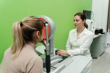 Korneanın şekli ve gücünün görsel tanımı için kornea topografisi göz görme testi. Kornea topografının kırmızı ışığı topoğrafya sınavında kadının üzerine parlıyor