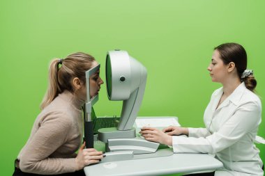 Korneanın şekli ve gücünün görsel tanımı için kornea topografisi göz görme testi. Optometrist göz hekimliği kliniğindeki kerato topografını kullanarak hastaların gözlerini tarıyor.