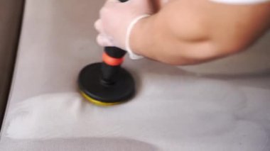 Kuru temizleme için fırçalı matkapla kanepeye deterjan sürerken 4K video. Kuru temizleme için evdeki kanepeye deterjan sürüyorum.