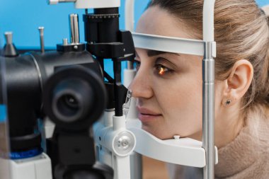 Göz doktoru, gözleri ve korneayı teşhis etmek için kesik lambadan gelen ışıkla çocuğun gözünü aydınlatıyor. Kesik lambasıyla pediatrik göz doktoru çocuğun gözlerini ve korneasını inceliyor.