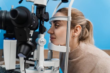 Göz doktoru, gözleri ve korneayı teşhis etmek için kesik lambadan gelen ışıkla çocuğun gözünü aydınlatıyor. Kesik lambasıyla pediatrik göz doktoru çocuğun gözlerini ve korneasını inceliyor.