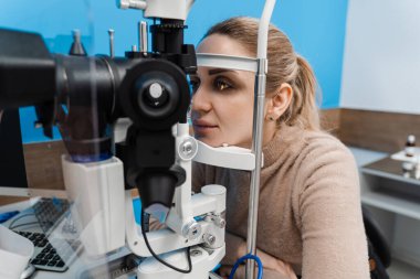 Göz doktoru, gözleri ve korneayı teşhis etmek için kesik lambadan gelen ışıkla çocuğun gözünü aydınlatıyor. Kesik lambasıyla pediatrik göz doktoru çocuğun gözlerini ve korneasını inceliyor.