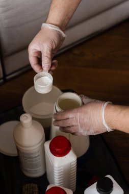 Temizlikçi kuru temizleme kimyasalları deterjanıyla döşeme mobilyalarını temizlemek ve kokuyu nötralize etmek için suyu karıştırıyor.