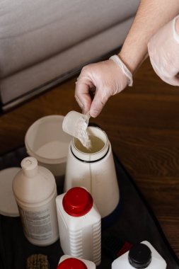 Temizlikçi kuru temizleme kimyasalları deterjanıyla döşeme mobilyalarını temizlemek ve kokuyu nötralize etmek için suyu karıştırıyor.