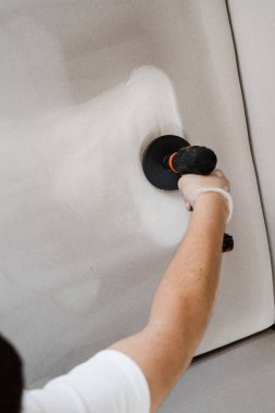 Deterjanı kanepeye sürtmek kuru temizleme için fırçayla delmek. Kuru temizleme için evdeki kanepeye deterjan sürüyorum.