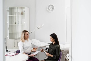 Kızın elinde rahim içi IUD cihazı var ve rahme yerleştirme işlemleri hakkında jinekoloğu dinle. Jinekoloji danışmanlığı
