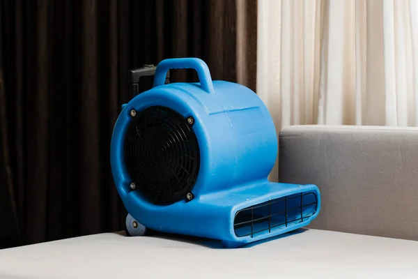 Process of drying sofa using floor dryer blower fan machine. Floor dryer blower fan machine drying wet couch after dry cleaning of upholstered furniture