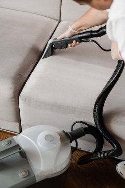 Temizlikçi kuru temizleme makinesiyle döşenmiş koltuktan toprak çıkarıyor. Kuru temizleme mobilyaları için elektrikli süpürge sökme makinesi ile kanepeyi temizliyorum.