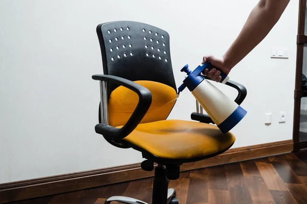 Spraying detergent on chair for dry cleaning using washing vacuum cleaner extractor machine. Process of dry cleaning for removing stains and dirt from armchair at home. Professional cleaning service