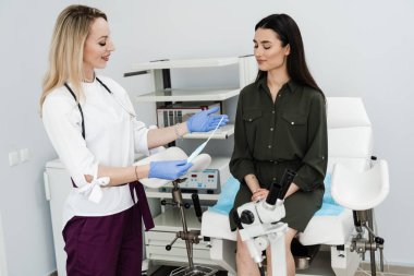 Doğum kontrolünün IUD intrauterine cihaz formu hakkında jinekoloğa danışıyorum. Jinekolog, jinekoloji kürsüsünde rahim içi cihazlar gösteriyor.