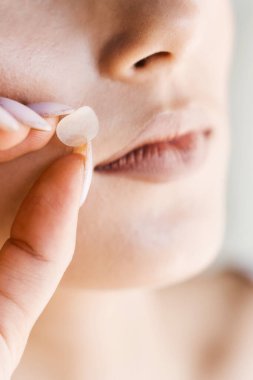 Kızın yanağına sivilce bandı yapıştırıyorum. Sivilce ve rosacea tedavisi için sivilce bandı kullanan genç bir kadın. Yüz gençleştirme, kozmetolojiyi temizleme.