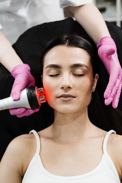 Thermal or radio frequency hardware RF lifting for smoothing wrinkles, improving skin tone and turgor. Tightening and rejuvenation of facial skin of girl at cosmetology procedure