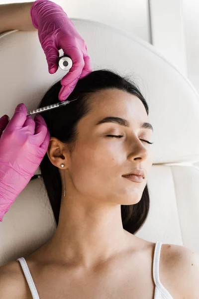 Cosmetologist is making mesotherapy injections in hair of girl. Mesotherapy treatment nourish the scalp and boost hair thickness and growth, helping to prevent hair loss