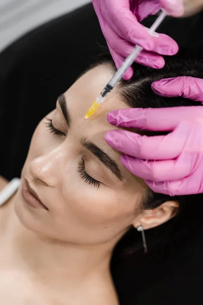 Botulinum toxin to relax and neutralize overactive muscles that cause wrinkles. Beautician is injecting botulinum toxin to correct mimic wrinkles and hyperhidrosis for young girl
