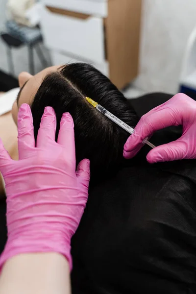 Cosmetologist is making mesotherapy injections in hair of girl. Mesotherapy treatment nourish the scalp and boost hair thickness and growth, helping to prevent hair loss