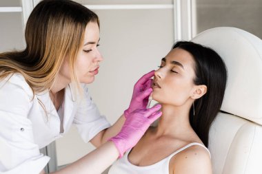Kozmetik uzmanı tıbbi klinikte büyütmek için dudaklarına hiyalüronik asit enjekte ediyor. Çekici bir kız için dudak büyütme iğneleri. Kozmetik yenileme yüz tedavisi