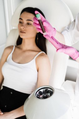 Kozmetik uzmanı, PRP Rich Plazma prosedürü için hasta kızın plazmasını almak için santrifüjde kan olan test tüpü yerleştirdi. Deri hacmini ve dokusunu iyileştirmek için trombosit Rich Plasma PRP