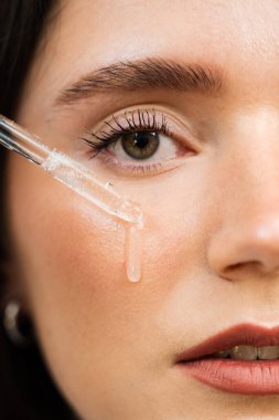 Kız yüz yüzeyine pipetten hyaluronik asit ya da serum atıyor. Genç bir kadın yüzüne nemlendirici serum sürüyor.