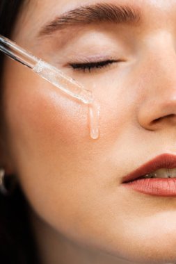 Çekici bir kız cilt bakımı için gerekli yağı döküyor. Genç bir kadın yüzüne nemlendirici serum sürüyor.