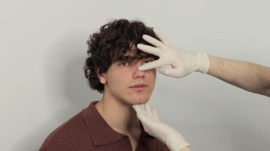 4k video rinoplasti burun ve septoplasti. KBB doktoru, burun ameliyatından önce erkek hastanın burnuna dokunuyor. Estetik ameliyattan önce burun büyüklüğünü ve şeklini düzeltmek için burun estetiği..
