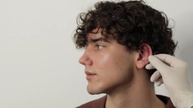 4K video cerrahı otoplasti ameliyatından önce erkek hastanın kulağını muayene ediyor. Estetik kulak ameliyatından önce hazırlanma, kulakların şekil, konum ve boyutunun değiştirilmesi prosedürü.