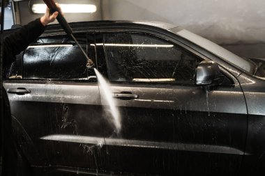 Köpüğü durulamak için arabaya su dökerek. self-servis araba yıkama. Yüksek basınçlı çamaşır makinesiyle müşterilerin arabasını yıkamak.