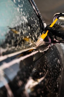 Yumuşak fırça ve temizleyici köpük kullanarak araba camlarını yıkama görüntüsünü kapat. Araba yıkama fırça kullanma ve köpük sürme. Araba yıkamada araba yıkama