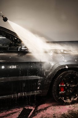 Aracın yüzeyindeki köpüğü yıkıyorum. Araba yıkama servisinde yüksek basınçlı su jeti ile cesedi temizlemek.